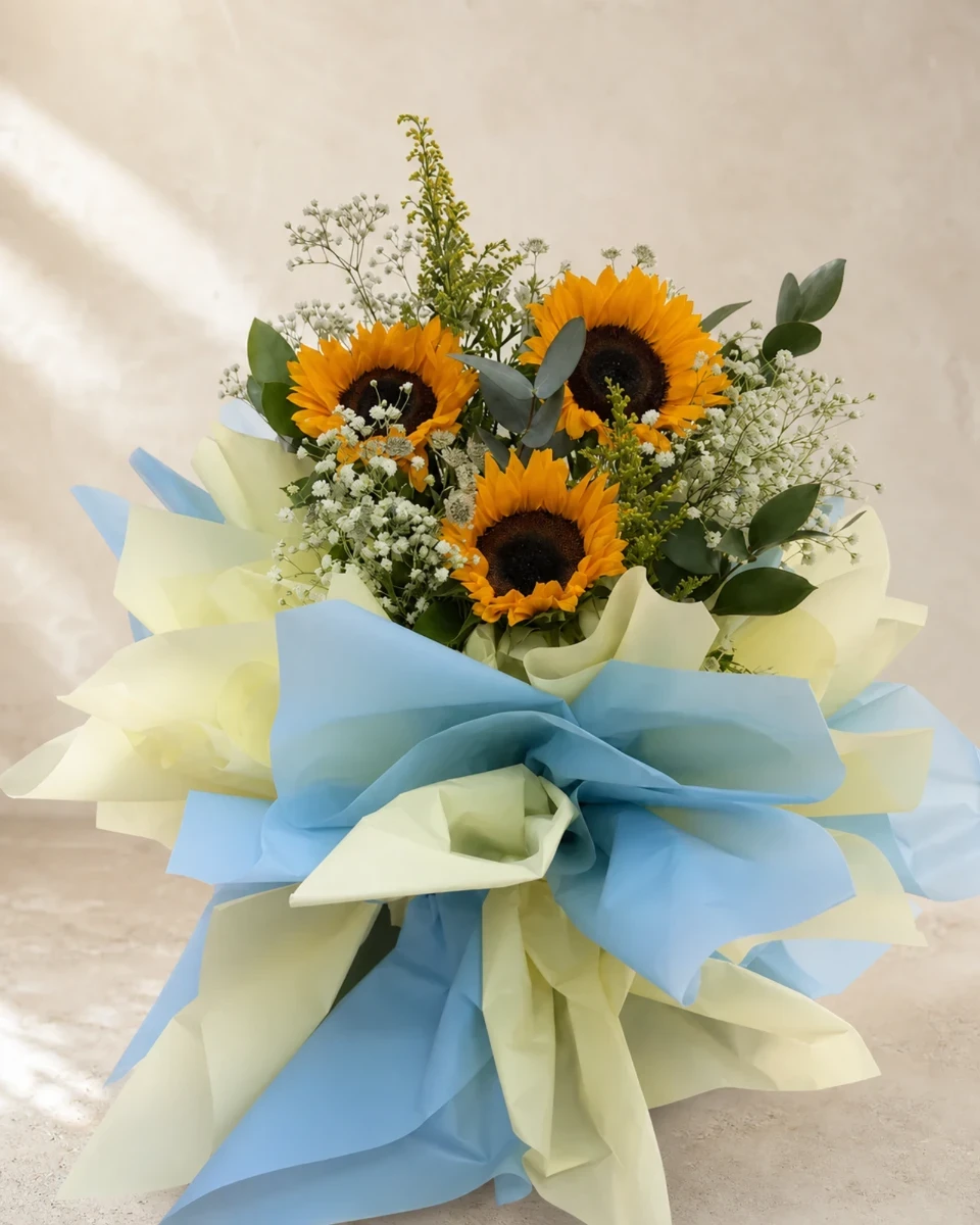 Hand-tied sunflower bouquet with eucalyptus, baby's breath and blue-and-cream wrapping